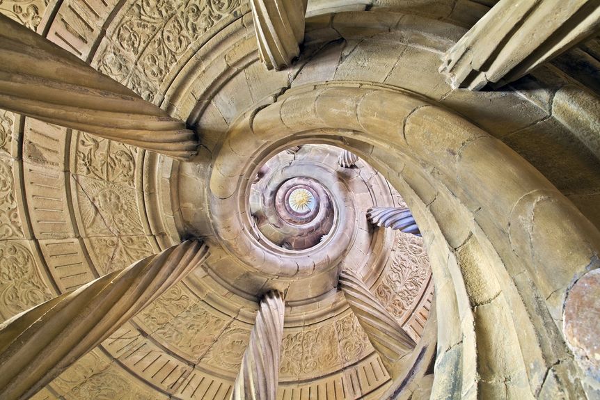 Blick vom Erdgeschoss durch die Spindel der Wendeltreppe zur stuckierten Sonne an der Decke